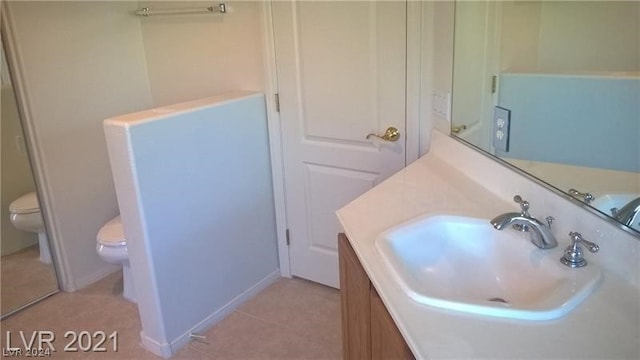 bathroom with toilet, tile flooring, and vanity