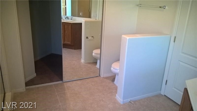 bathroom with toilet, tile flooring, and vanity