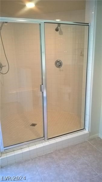 bathroom with tile flooring and a shower with door