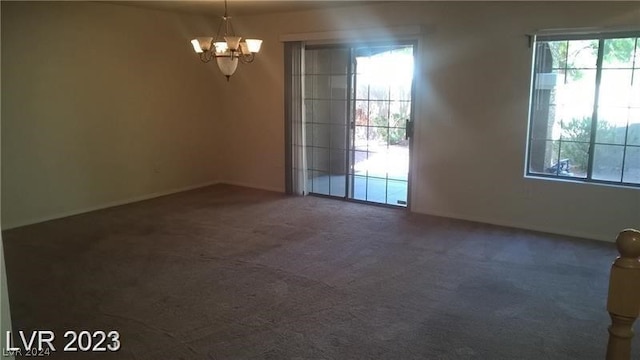 spare room with a chandelier and dark colored carpet