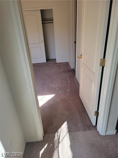 unfurnished bedroom with dark colored carpet and a closet