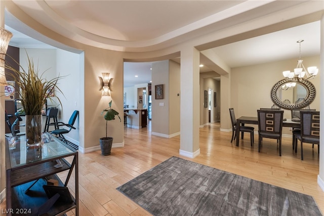 interior space featuring a tray ceiling, light hardwood / wood-style floors, and a chandelier