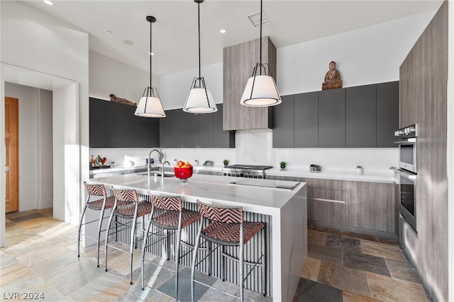 kitchen featuring sink, an island with sink, a breakfast bar, and pendant lighting