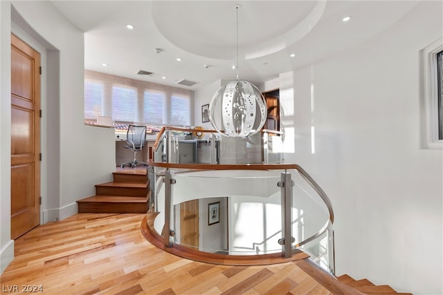 stairs featuring a raised ceiling and light wood-type flooring