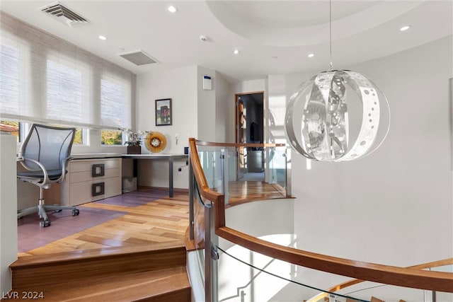 home office featuring a raised ceiling, built in desk, and hardwood / wood-style floors