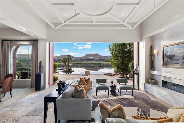 interior space with coffered ceiling, a high end fireplace, and light tile floors