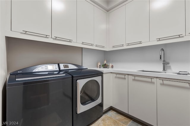 laundry area featuring washer and dryer, cabinets, sink, and light tile floors