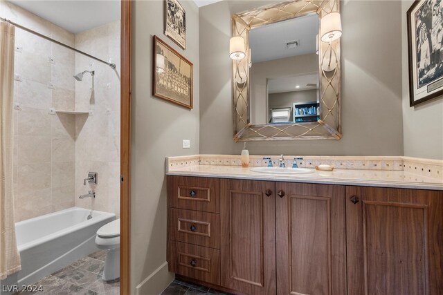 full bathroom with tile flooring, toilet, tiled shower / bath, and vanity with extensive cabinet space