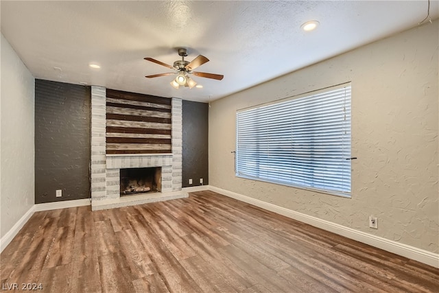 unfurnished living room with a fireplace, wood-type flooring, and ceiling fan