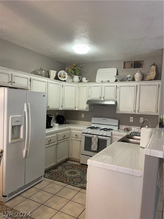 kitchen featuring light tile patterned floors, sink, white refrigerator with ice dispenser, gas range oven, and kitchen peninsula