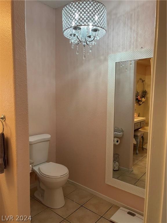 bathroom featuring tile patterned floors, toilet, and a chandelier