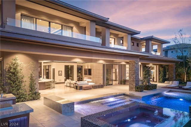 back house at dusk featuring a patio, an outdoor living space, and an in ground hot tub