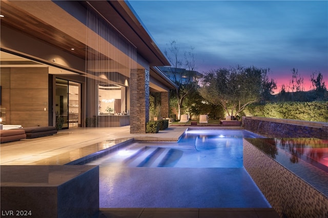 pool at dusk with a patio area