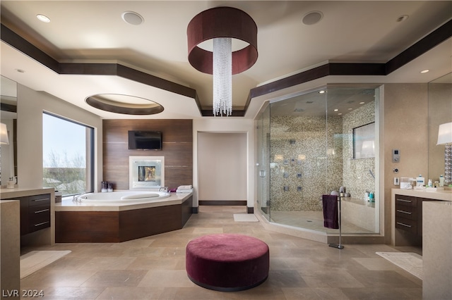 bathroom with a tray ceiling, independent shower and bath, vanity, and tile floors