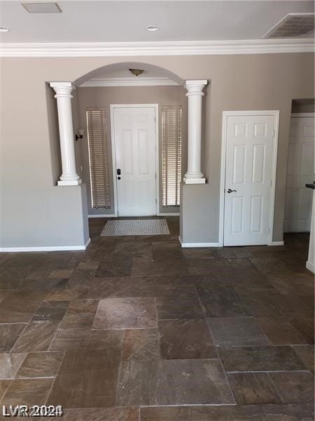 foyer with decorative columns, crown molding, and dark tile patterned floors