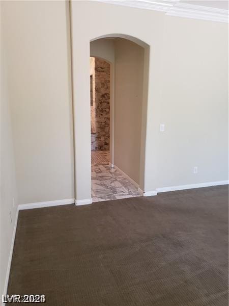 spare room with crown molding and dark colored carpet