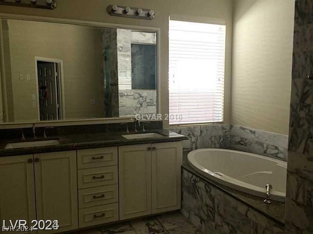 bathroom with vanity and tiled tub