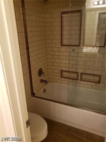 bathroom featuring enclosed tub / shower combo and toilet