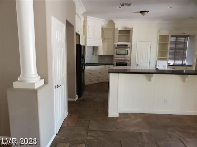 kitchen with a breakfast bar, crown molding, black refrigerator, stainless steel double oven, and decorative backsplash