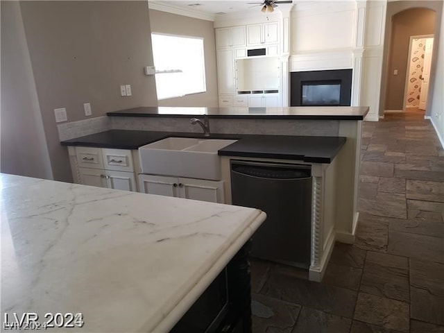 kitchen featuring sink, white cabinetry, black dishwasher, ornamental molding, and a large fireplace