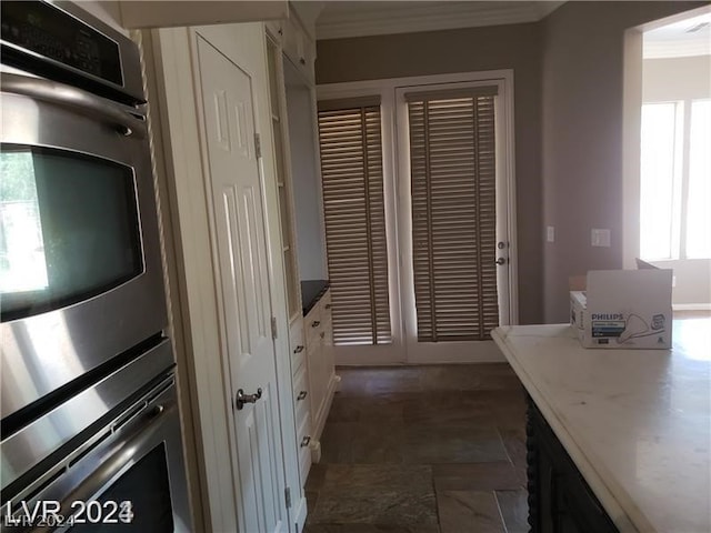 kitchen featuring crown molding, white cabinets, and double oven