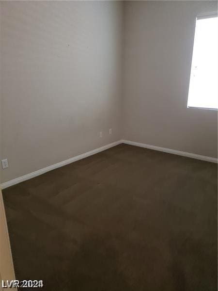 spare room featuring dark colored carpet