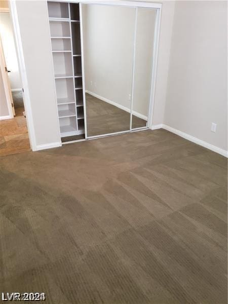 unfurnished bedroom featuring dark carpet and a closet