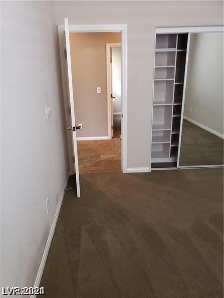 unfurnished bedroom with dark colored carpet and a closet