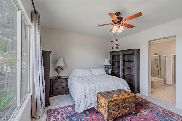 bedroom featuring light carpet, ensuite bath, and a ceiling fan