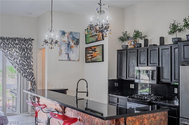 kitchen with stainless steel appliances, dark countertops, pendant lighting, and an inviting chandelier