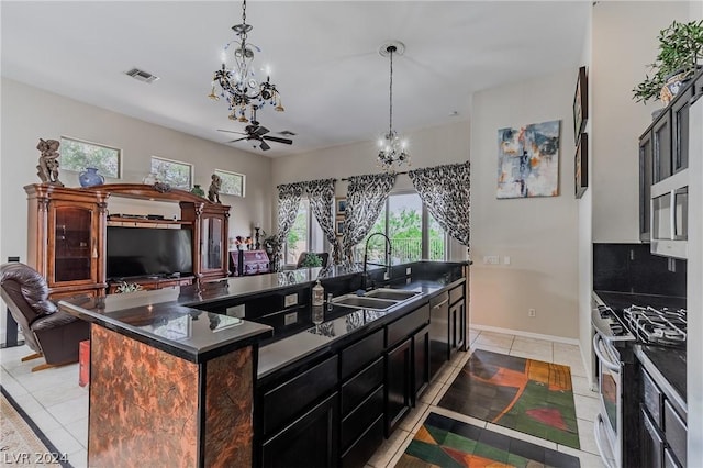 kitchen featuring dark countertops, a center island with sink, appliances with stainless steel finishes, and a notable chandelier