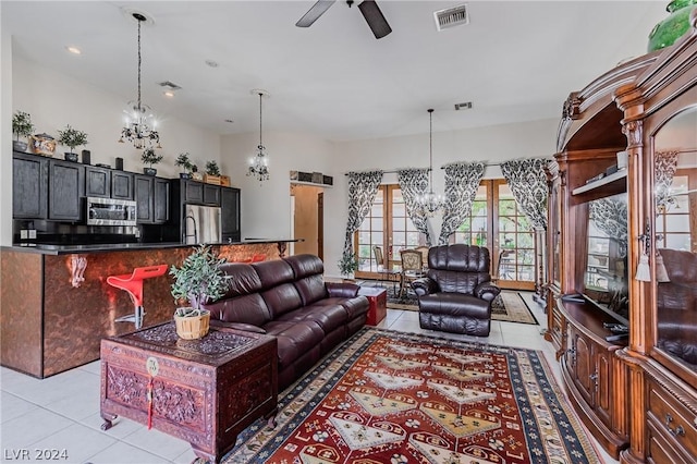 living area with light tile patterned floors, ceiling fan with notable chandelier, and visible vents