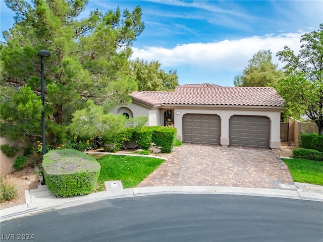 mediterranean / spanish home featuring a tiled roof, decorative driveway, an attached garage, and stucco siding