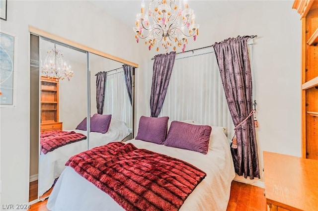 bedroom with light wood-type flooring, a chandelier, and a closet