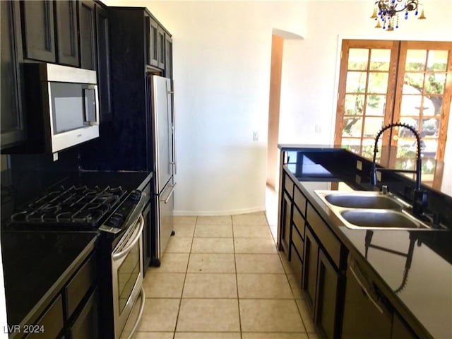 kitchen with dark countertops, backsplash, appliances with stainless steel finishes, light tile patterned flooring, and a sink