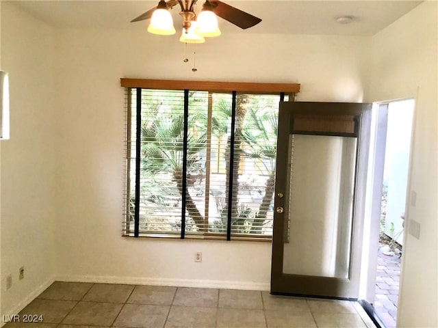 unfurnished room featuring light tile patterned floors, ceiling fan, and baseboards