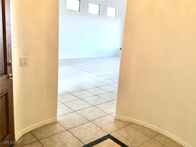 corridor featuring baseboards and light tile patterned floors