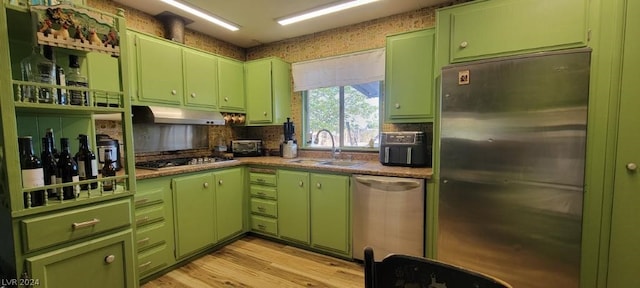 kitchen with sink, light hardwood / wood-style flooring, green cabinetry, and appliances with stainless steel finishes