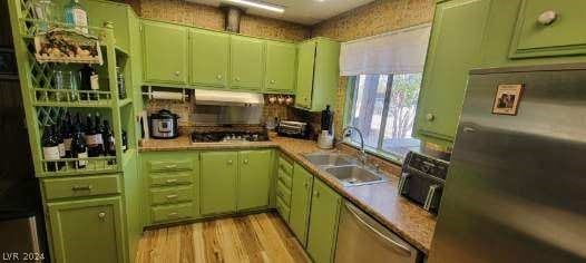 kitchen featuring appliances with stainless steel finishes, sink, light hardwood / wood-style flooring, and green cabinetry