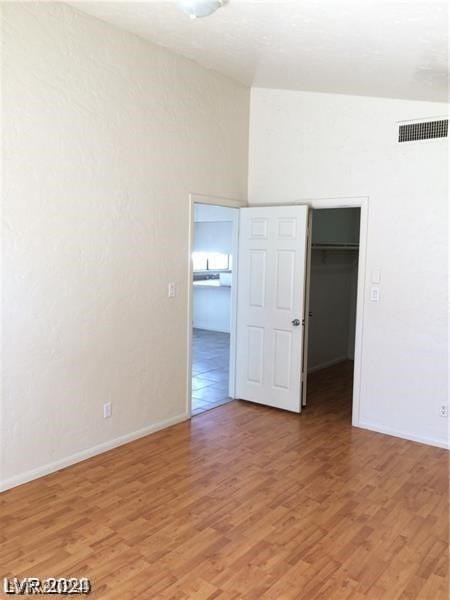 unfurnished room featuring hardwood / wood-style floors and lofted ceiling