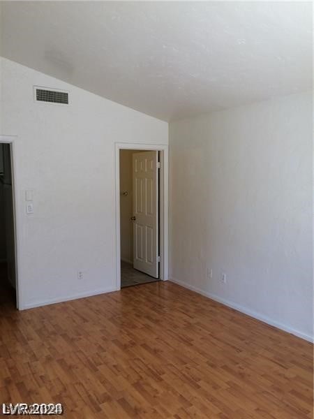 spare room featuring wood-type flooring and lofted ceiling