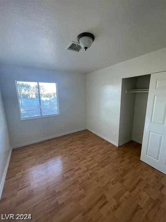 unfurnished bedroom with a closet and hardwood / wood-style flooring