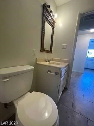 bathroom with toilet, vanity with extensive cabinet space, and tile flooring