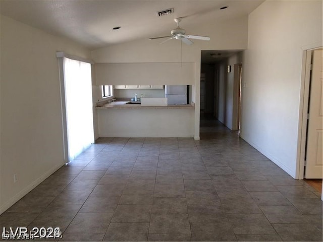 kitchen featuring lofted ceiling, ceiling fan, stainless steel fridge, and dark tile floors