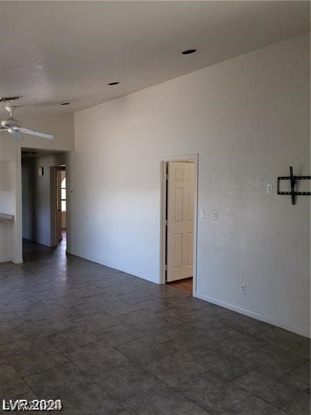 empty room with dark tile floors and ceiling fan