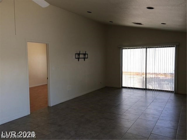 empty room featuring tile floors, high vaulted ceiling, and a textured ceiling