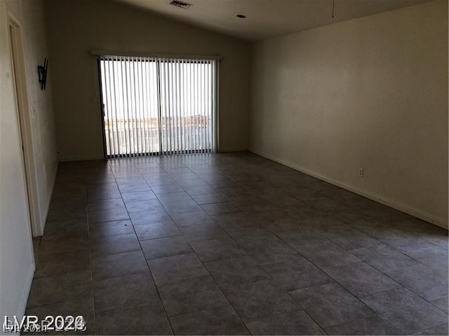 tiled spare room featuring lofted ceiling