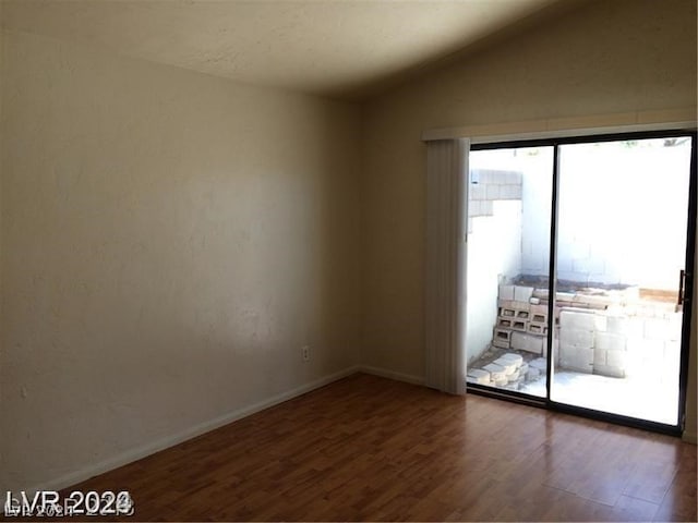 unfurnished room with dark wood-type flooring and lofted ceiling