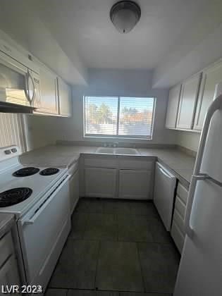 kitchen with white cabinets, sink, and white appliances