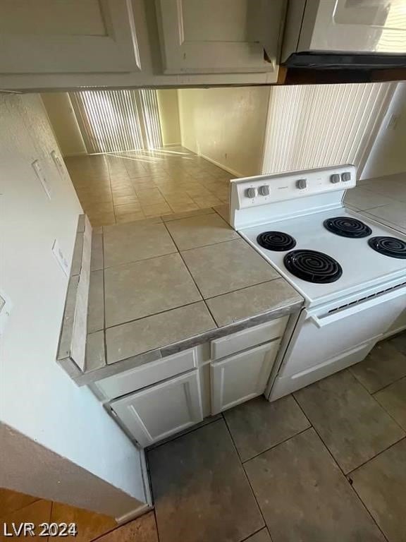 kitchen with tile counters, white electric range, and tile floors